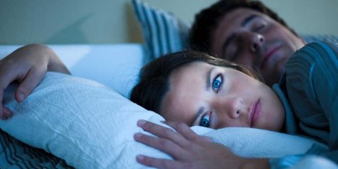 Femme allongée insomniaque à côté de son mari