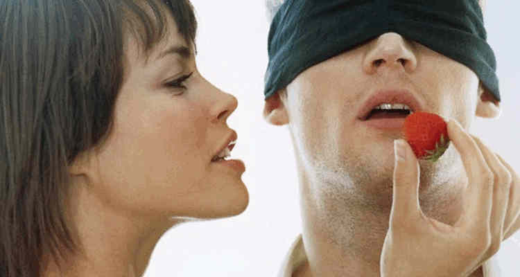 Femme qui bande les yeux d'un homme pour le manipuler